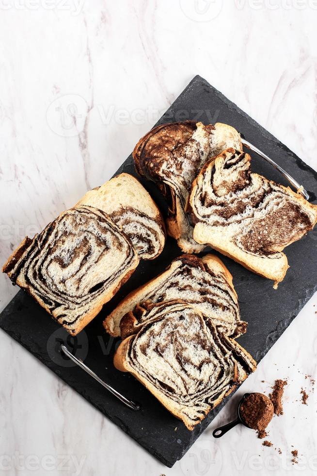 Schokoladen-Babka oder Brioche-Brot. hausgemachtes süßes Wüstengebäck - Schokoladenstrudelbrot mit Marmorstruktur. in Scheiben geschnitten auf weißem Hintergrund foto