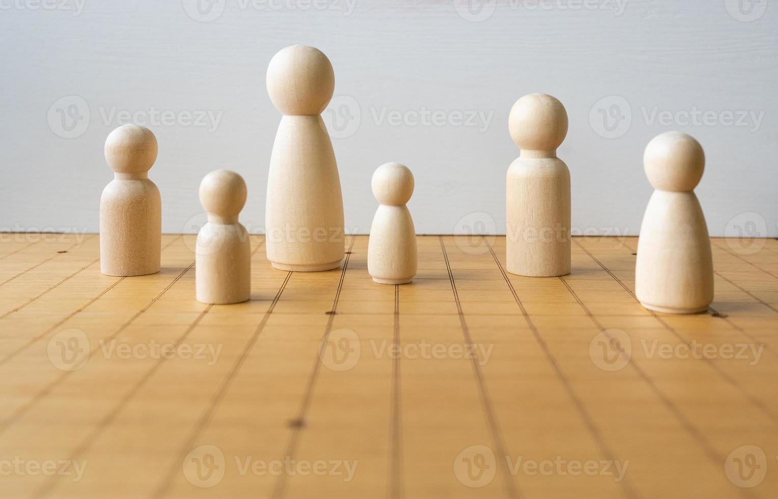 Holzfigur unterschiedlicher Größe, die auf einem Schachbrett platziert wird und die Vielfalt von Menschen und Familien darstellt foto