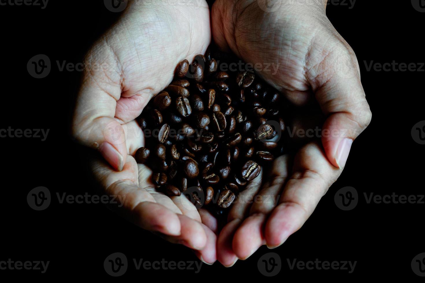 Kaffeebohnen in den Händen des Herzens auf dunklem Holztisch foto