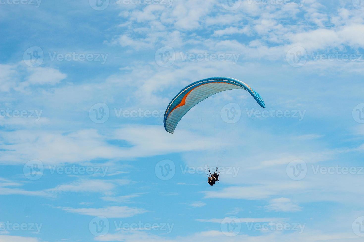 Gleitschirm-Tandem fliegt über das Meer mit blauem Wasser und Strand an strahlend sonnigen Tagen. foto