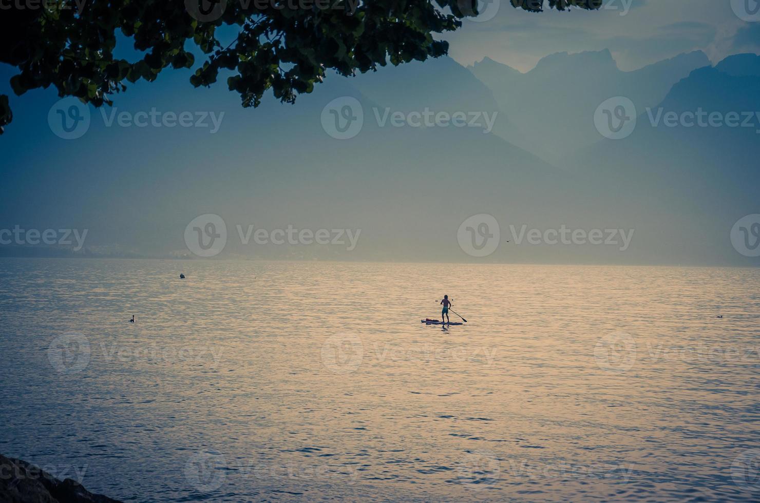 Mann auf einem Surfbrett mit Paddel auf dem Genfer See, Schweiz foto