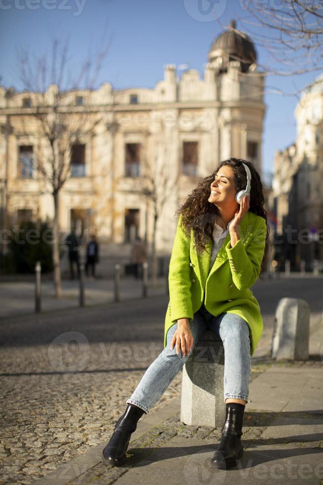 junge Frau hört Musik mit Smartphone auf der Straße und hält Kaffee zum Mitnehmen foto