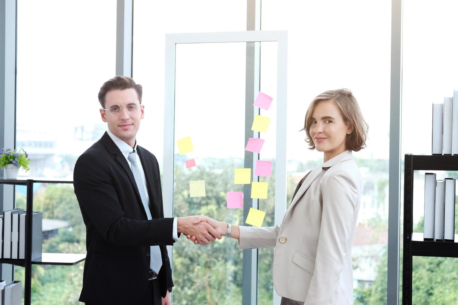 erfolgreicher geschäftsmann und geschäftsfrau glücklich und schütteln sich die hände, nachdem sie sich zur partnerschaft in einem modernen büro getroffen haben foto