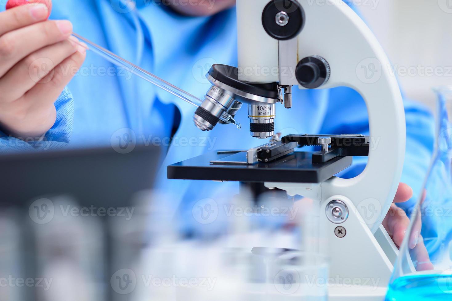 wissenschaftler bereiten proben vor, um die proben mit einem mikroskop im labor zu untersuchen, und tropfen die lösung auf eine glasplatte mit einer pipette auf dem mikroskop. , pharmazeutisches Konzept, erfand den Impfstoff foto