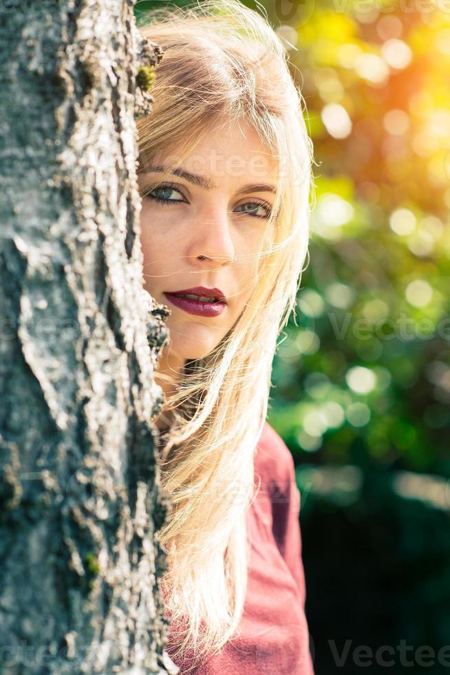 blondes Mädchen hinter einem Baum foto