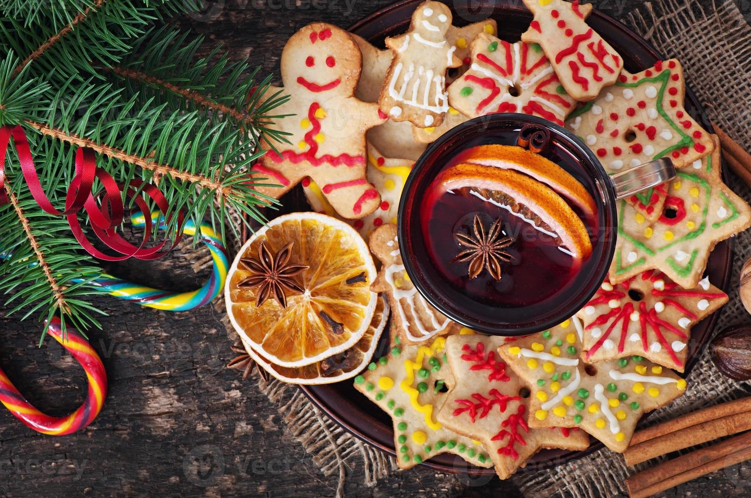 wärmender glühwein, gewürze und lebkuchenplätzchen auf einem hölzernen hintergrund im rustikalen stil foto