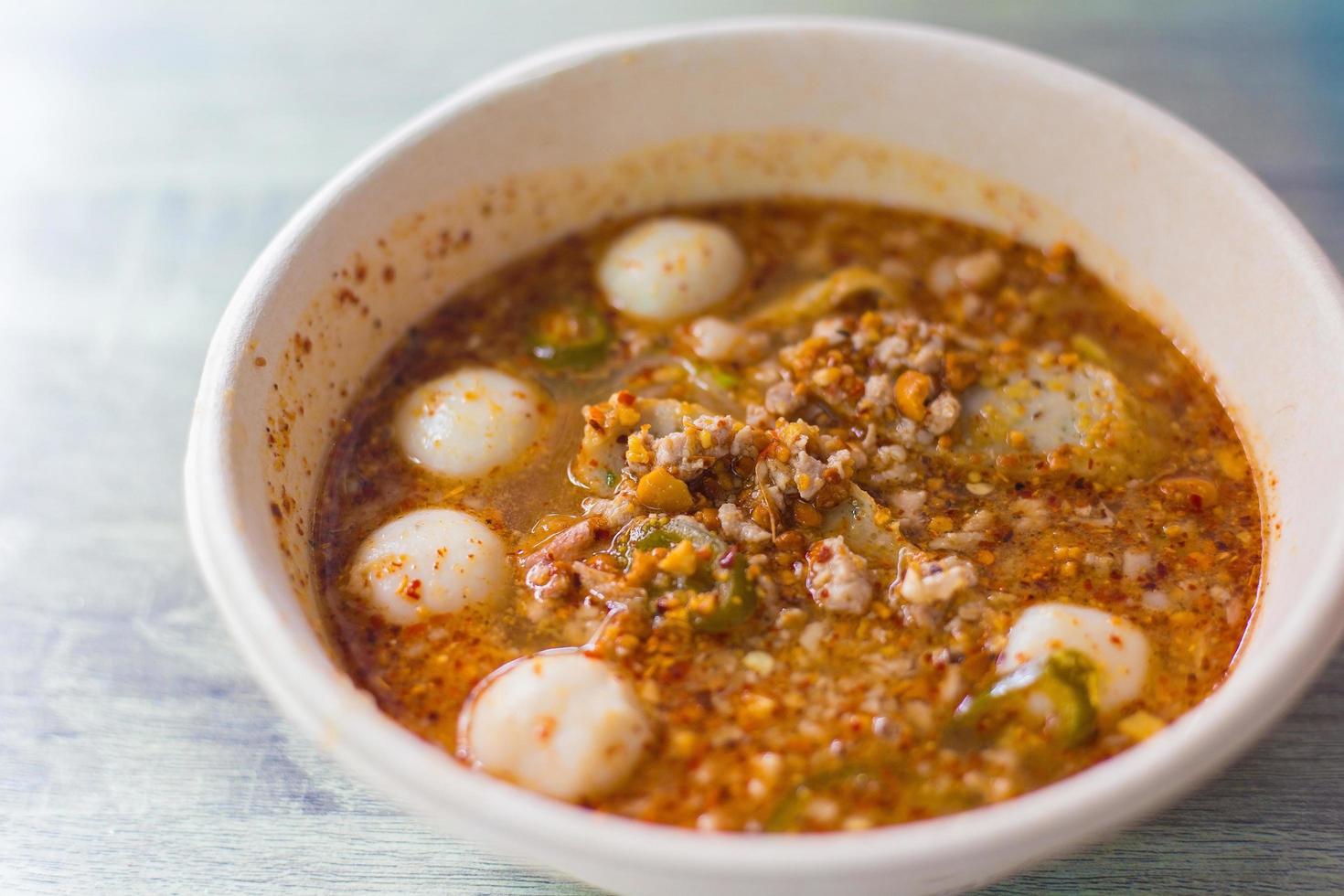 closeup würzige tom yum schweinefleischnudeln mit suppe, die fischbällchen, kühlpaste und limettensaft enthält. Diese Nudeln haben einen scharfen, würzigen und sauren Geschmack im thailändischen Essensstil. foto