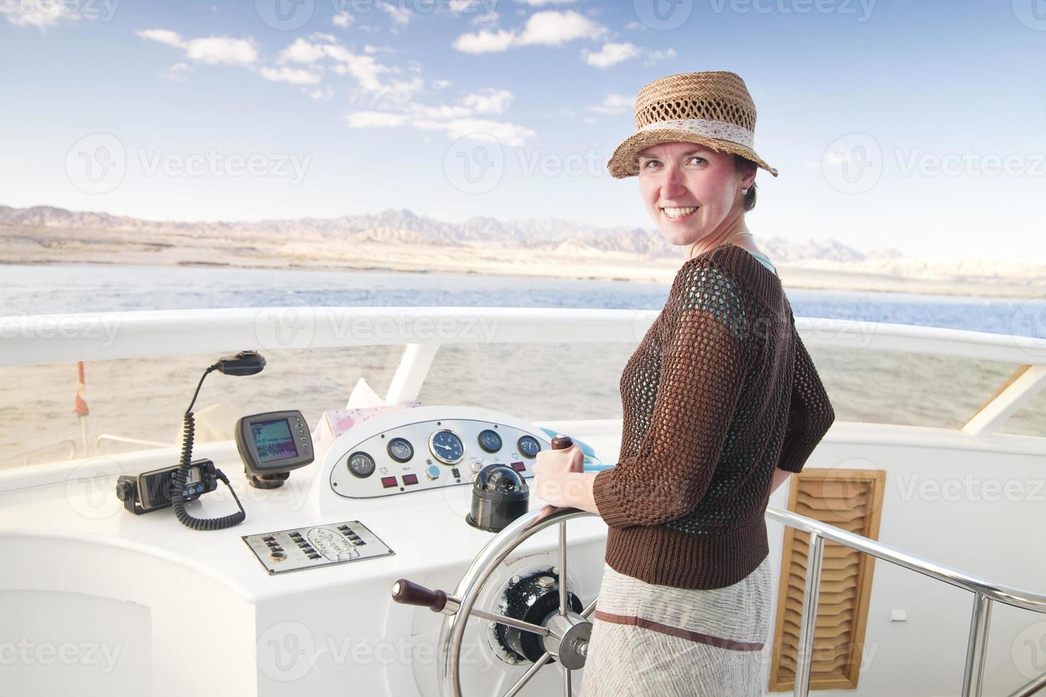 attraktive junge Frau, die ein Boot steuert foto