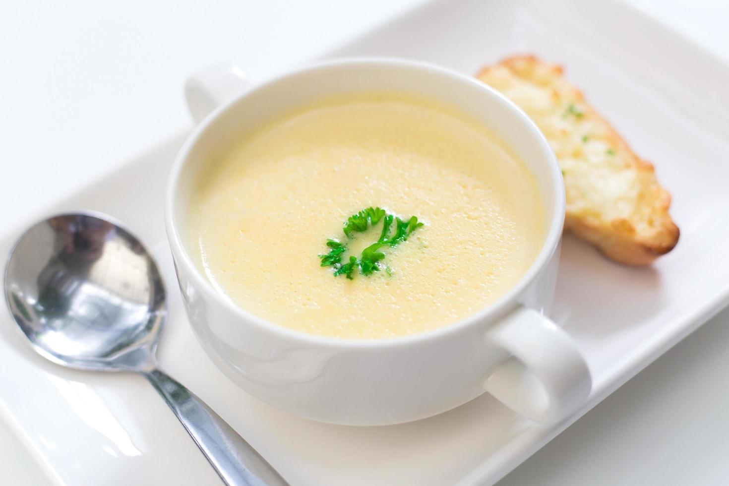 köstliche Maissuppe in einer weißen Schüssel, serviert mit Brot. foto