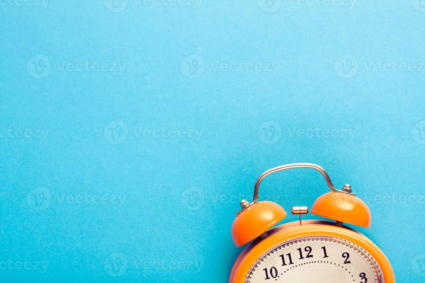 orangefarbener Wecker im Vintage-Stil mit Glocken auf blauem Hintergrund mit freiem Kopierplatz für Text. foto