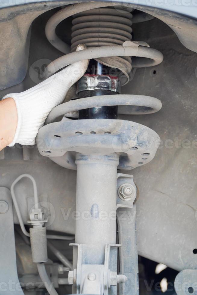 Mechaniker inspiziert Auto in Garage mit alten Stoßdämpfern. Konzept foto