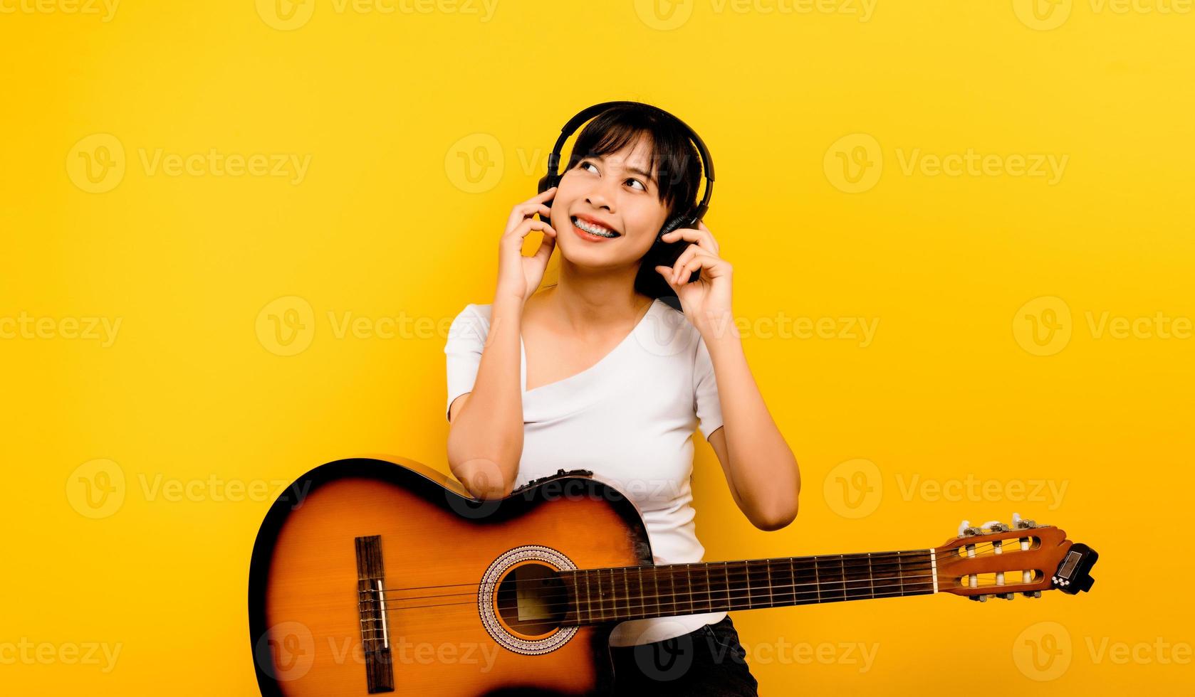 frau, die musik hört eine junge asiatische frau in einem weißen kleid lächelt glücklich. happy people lifestyle concept copy space mockup hören sie musik mit kopfhörern foto