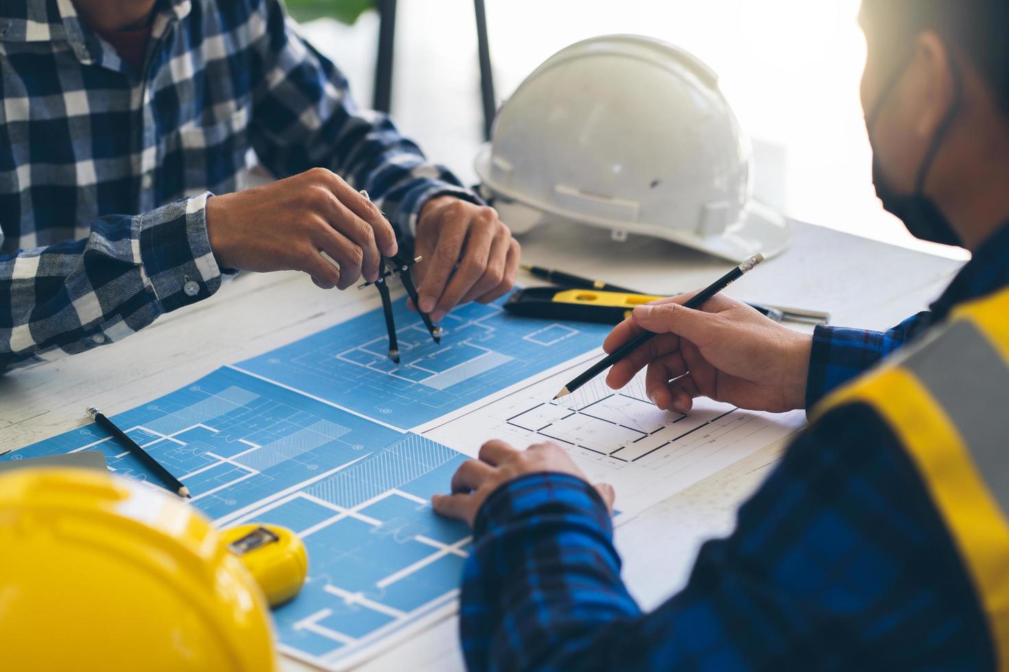 handzeichnungsplan des ingenieurs der person auf blaupause mit architektenausrüstung, architekten, die am tisch diskutieren, teamarbeit und arbeitsablaufkonstruktionskonzept. foto