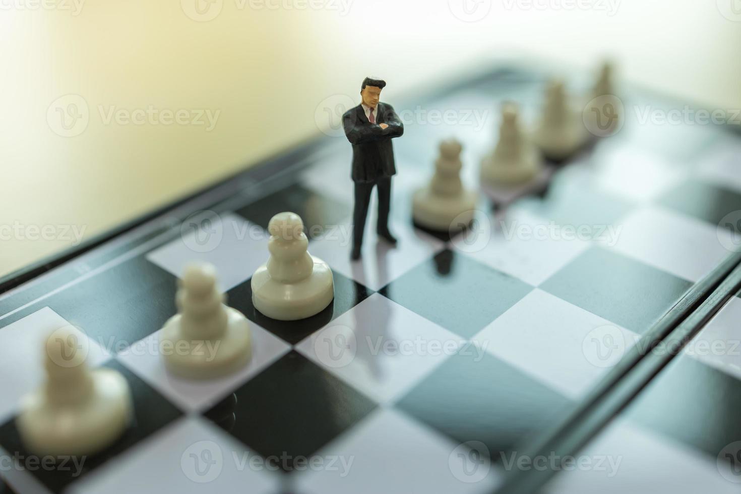 Geschäfts-, Teamwork- und Planungskonzept. Nahaufnahme von Geschäftsmann Miniatur Menschen Figur stehend auf Schachbrett zwischen Bauern Schachfiguren und kopieren. foto