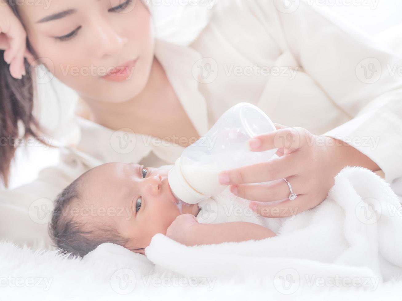Eine schöne asiatische Frau lag mit Liebe und Wertschätzung neben ihrem neugeborenen Baby und fütterte sie mit Glück foto