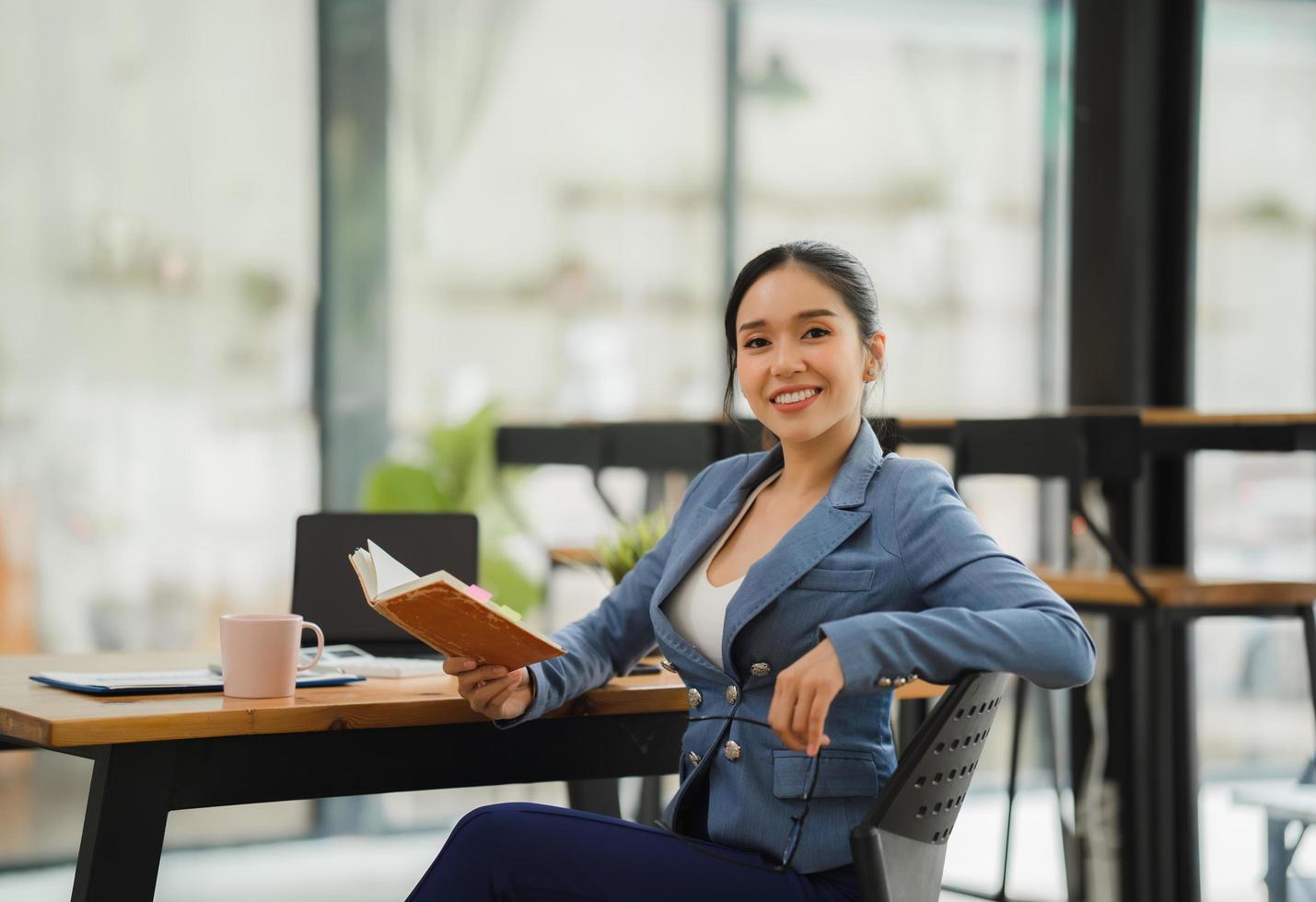 Porträt einer asiatischen jungen Frau, die im Büro an Laptop und Finanzbericht arbeitet. foto