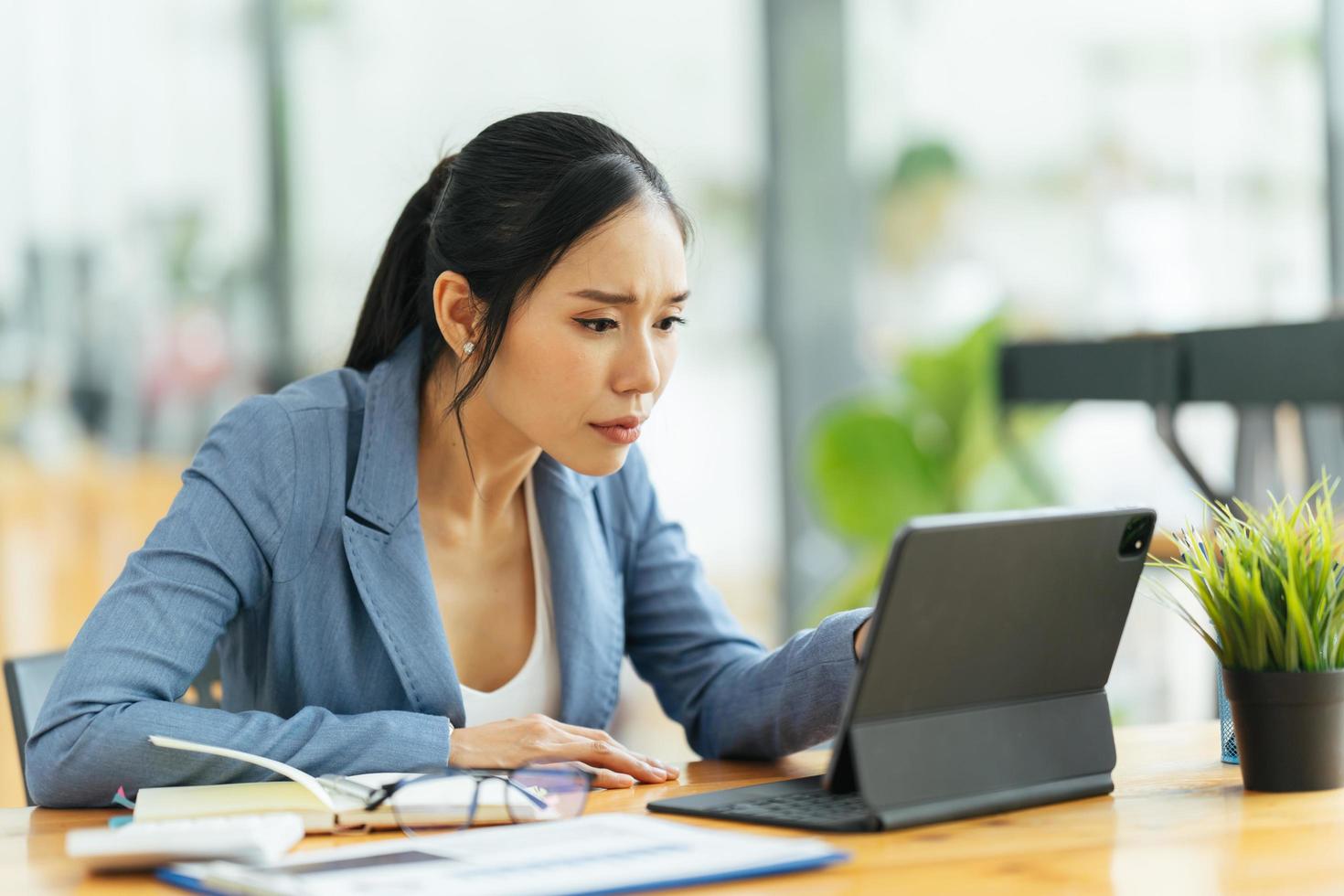 Porträt einer asiatischen jungen Frau, die im Büro an Laptop und Finanzbericht arbeitet. foto