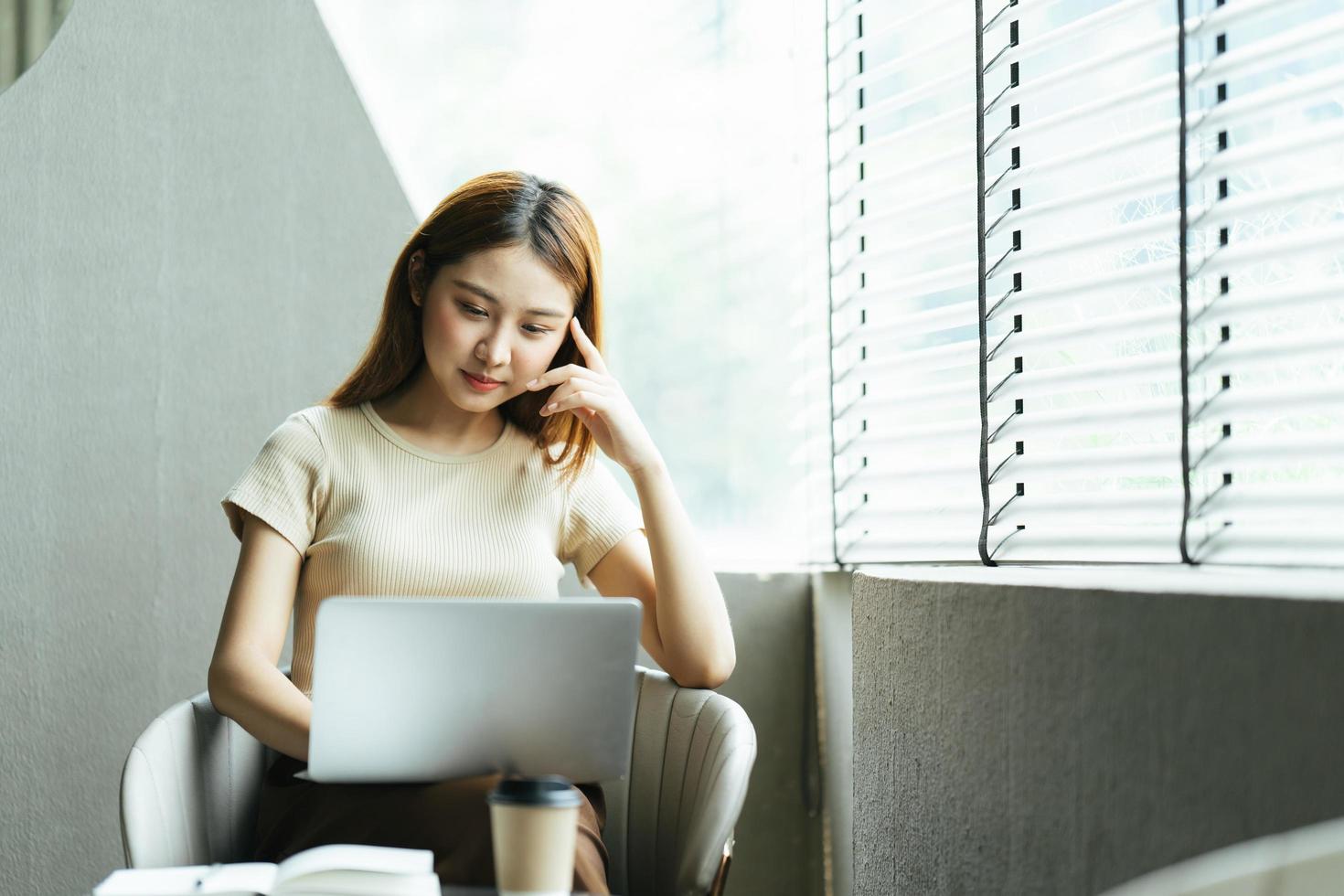 porträt einer schönen asiatischen frau, die im sommer drinnen im café-restaurant sitzt, mit intelligenter drahtloser technologie, computer-laptop und smartphone, entspannende kaffeepause im café-restaurant. foto