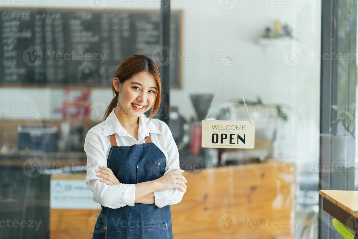 lächelnde Kellnerin oder Café-Geschäftsinhaberin, die in die Kamera schaut foto