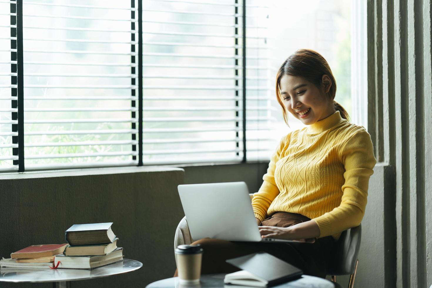 porträt einer schönen asiatischen frau, die im sommer drinnen im café-restaurant sitzt, mit intelligenter drahtloser technologie, computer-laptop und smartphone, entspannende kaffeepause im café-restaurant. foto