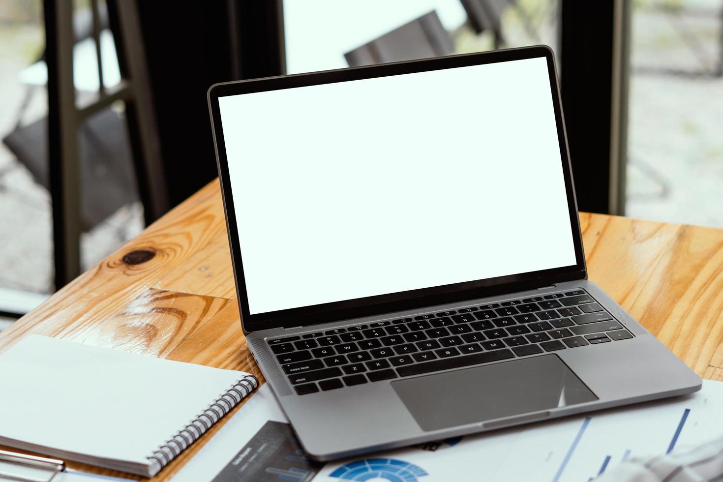 Seitenansicht des zeitgenössischen Arbeitsplatzes mit Laptop-Computer, Notizbuch, Kaffeetasse und Schreibwaren auf Holztisch. Beschneidungspfad. foto