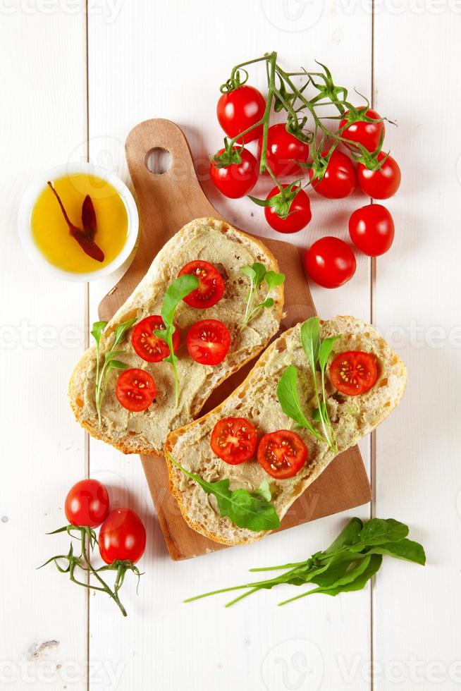 Sandwich mit Kirschtomaten und Avocado- und Rucolacreme foto