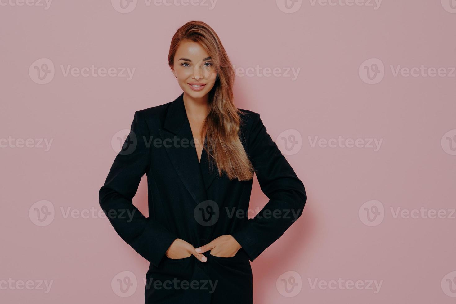 glückliche Geschäftsfrau, die auf rosa Hintergrund in die Kamera lächelt foto