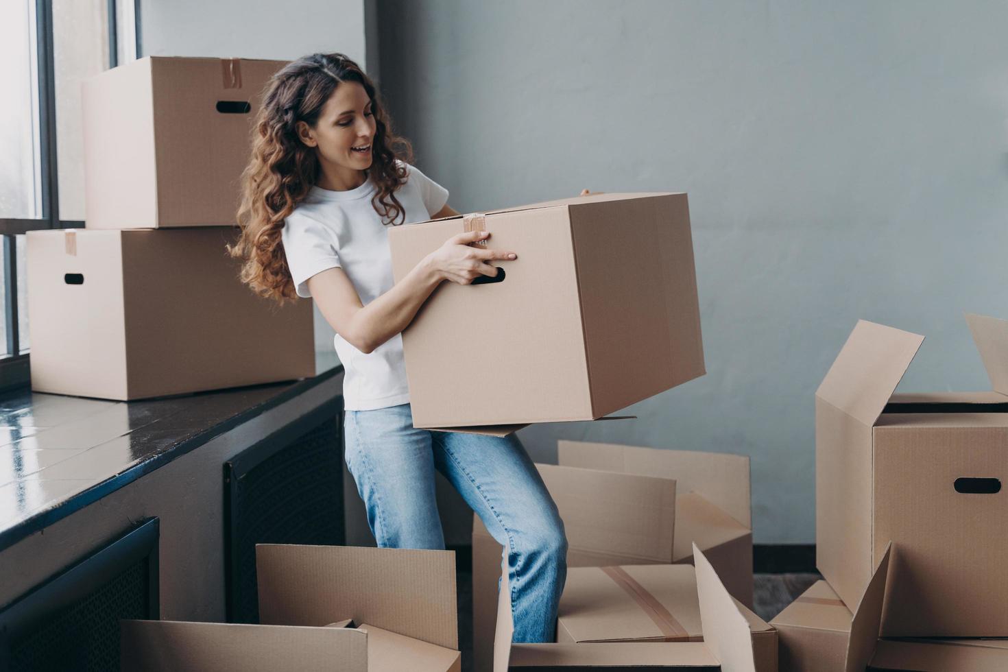 junge dame im weißen t-shirt trägt pappkarton. hispanische Frau, die Dinge packt und geht. foto