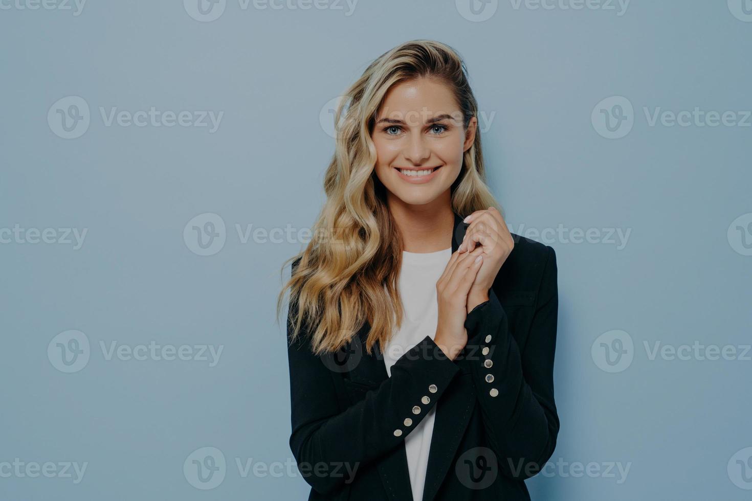 süße positive Studentin in stilvollem Freizeitoutfit, die an der blauen Studiowand posiert foto