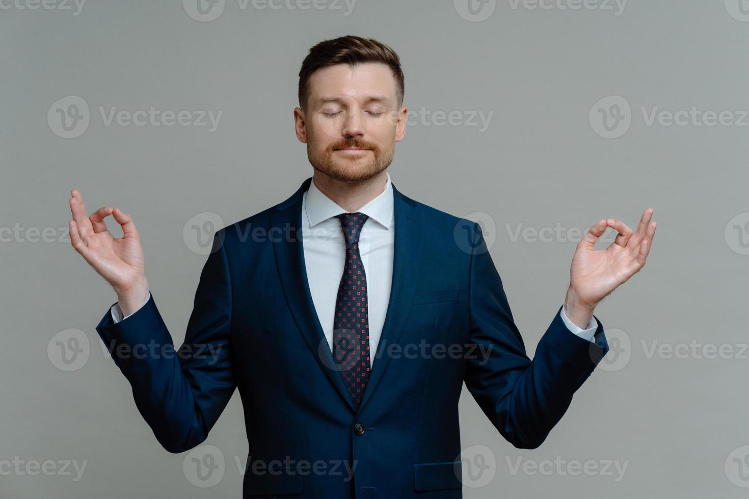 Ruhiger Geschäftsmann im Anzug meditiert und klingelt Yoga-Übung foto