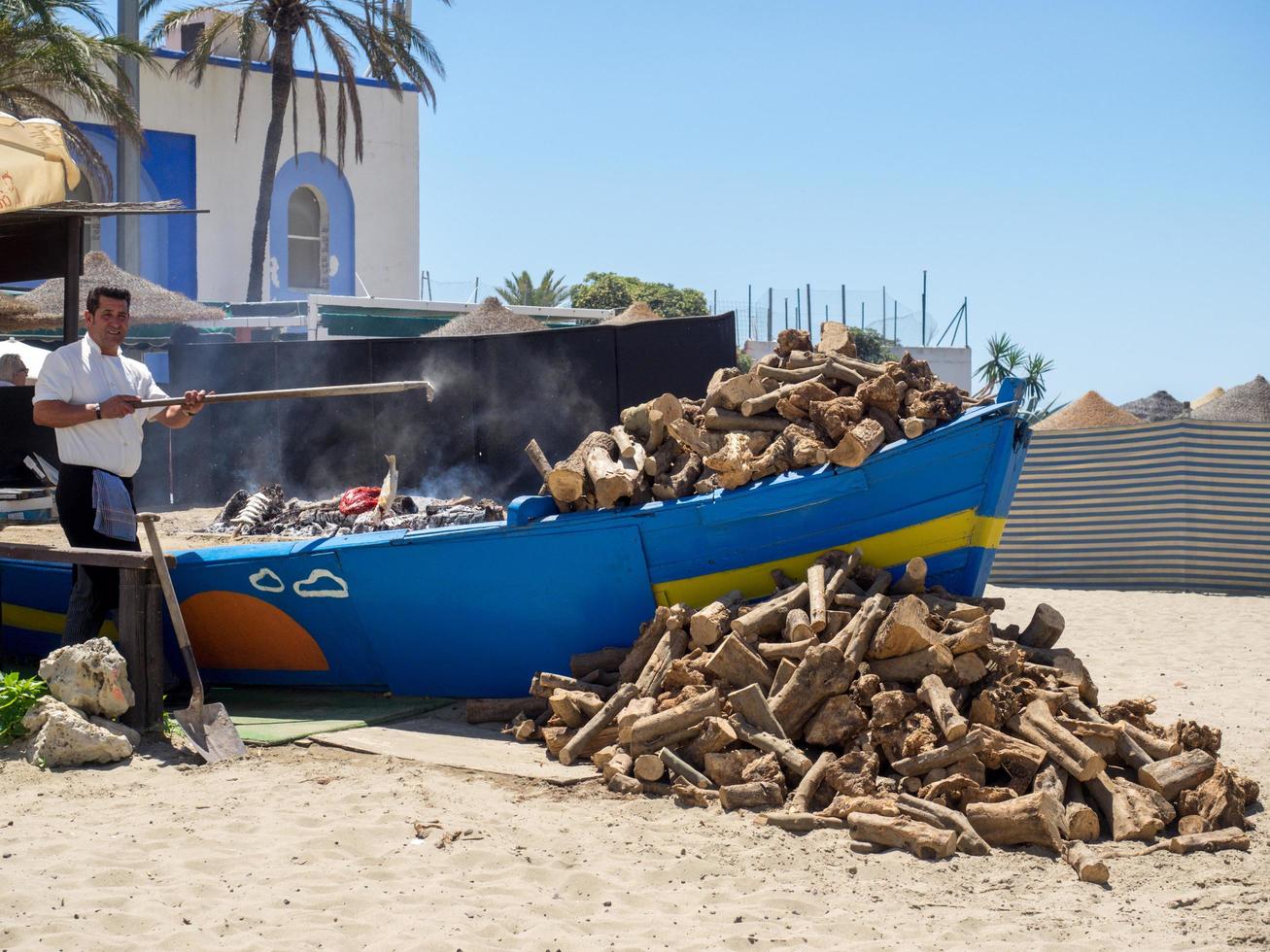 marbella, andalusien, spanien, 2014. mann, der fisch am strand kocht foto