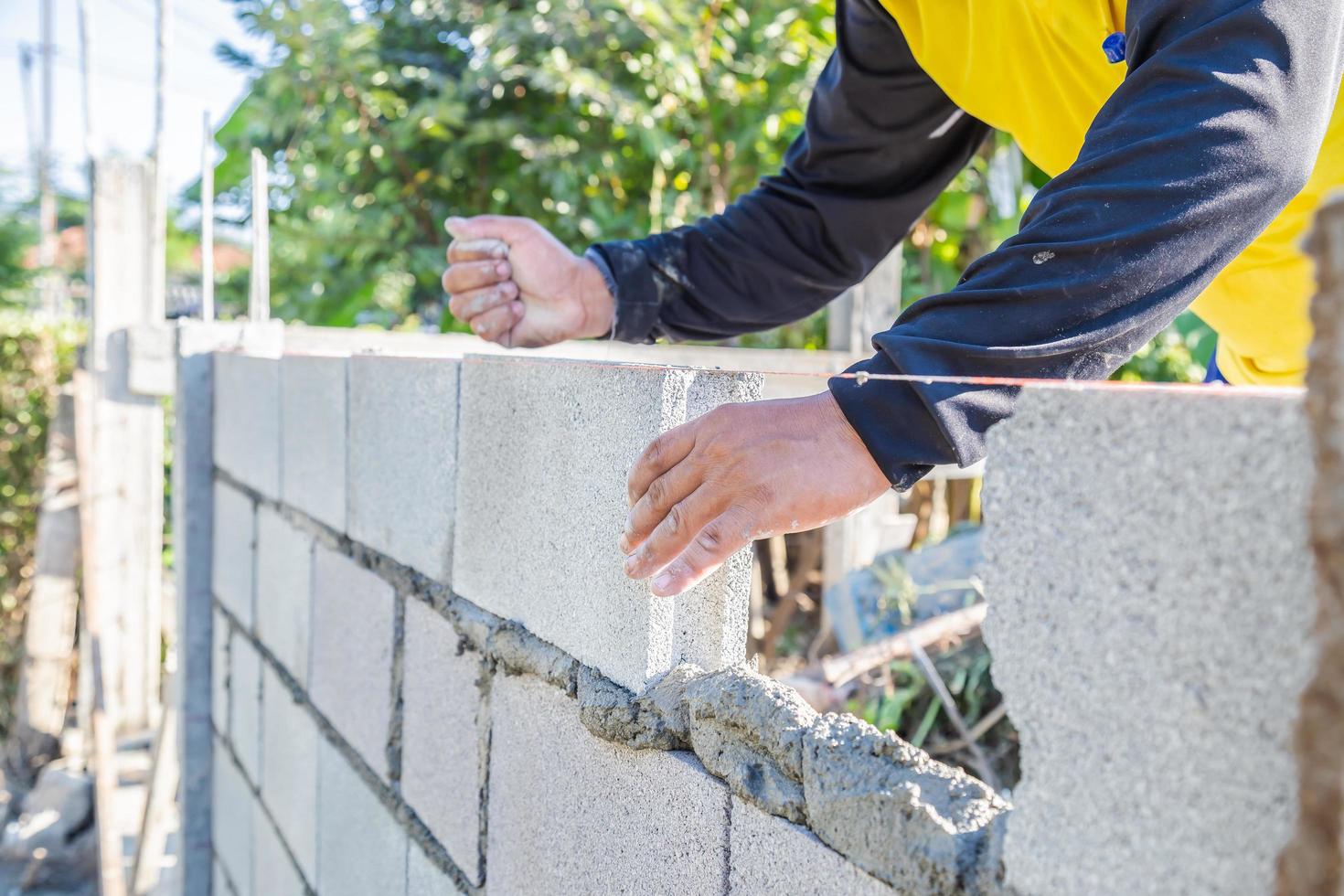 Arbeiter Mauerwerk bauen Wände mit Zementblöcken und Mörtel. foto
