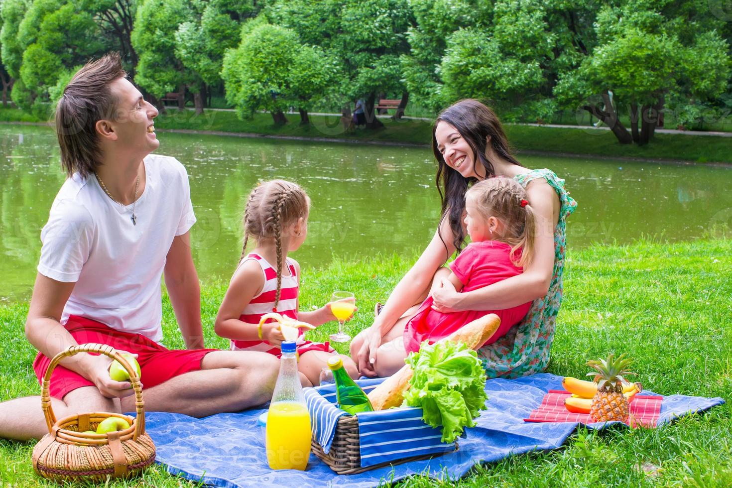 glückliche junge Familie Picknick im Freien in der Nähe des Sees foto