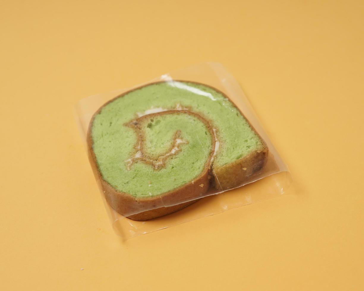 mit Rahmbutter bestrichene Brotscheiben werden dann gerollt und in Scheiben geschnitten. Brot in Form einer Rolle. Die grüne Farbe zeigt normalerweise den Pandan-Geschmack im Brot an. geschmack von indonesischem kuchen. Fokusunschärfe. foto