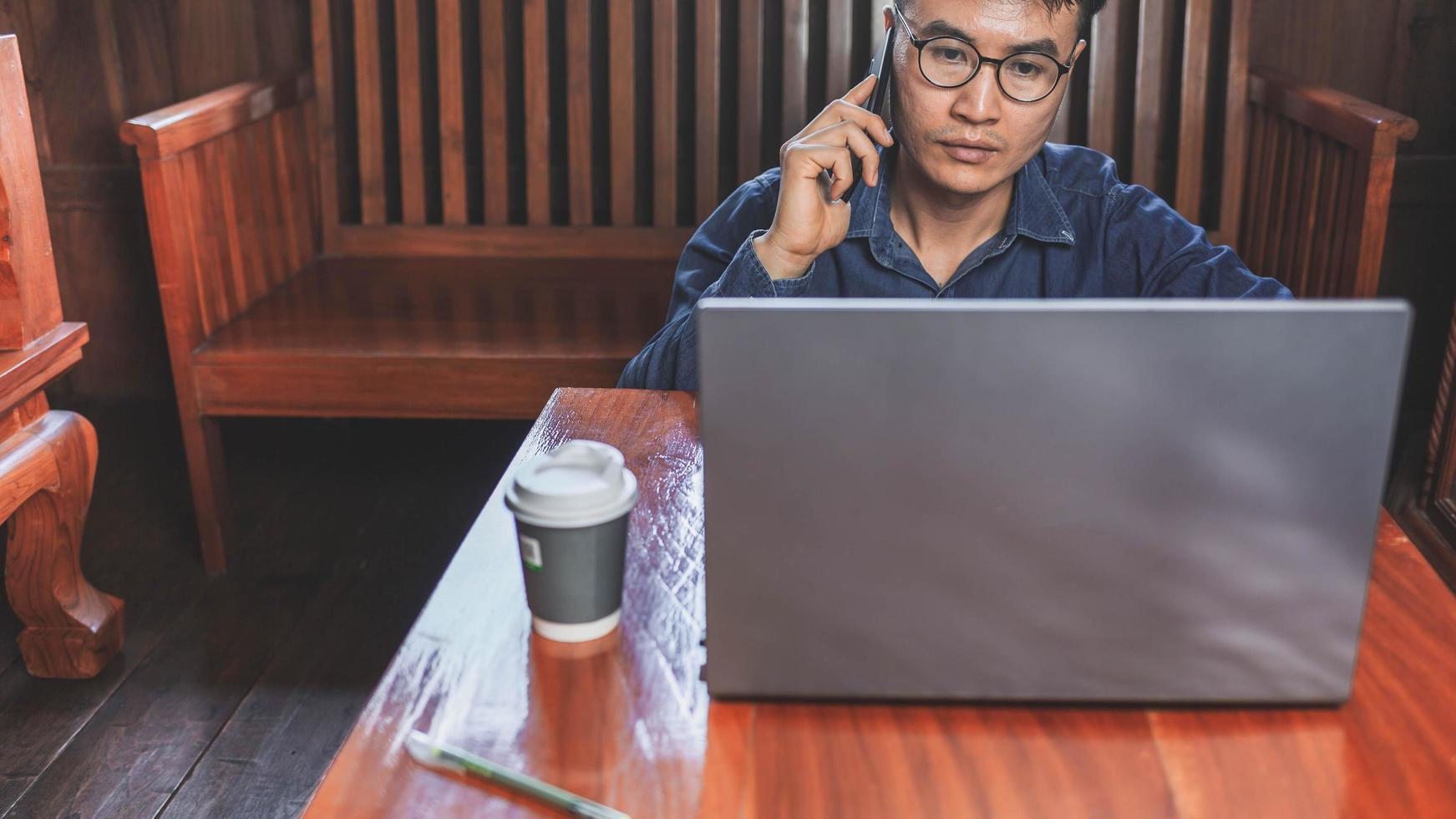 junger Mann, der von zu Hause aus mit Smartphone und Notebook arbeitet. foto