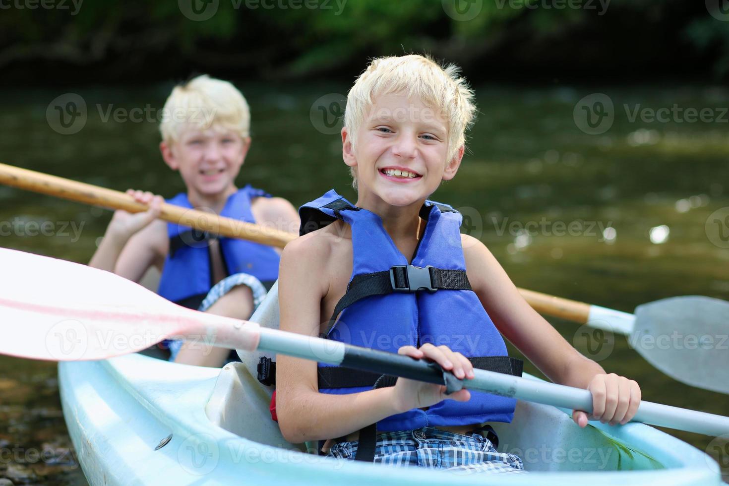 zwei glückliche Jungen, die Kajak auf dem Fluss genießen foto