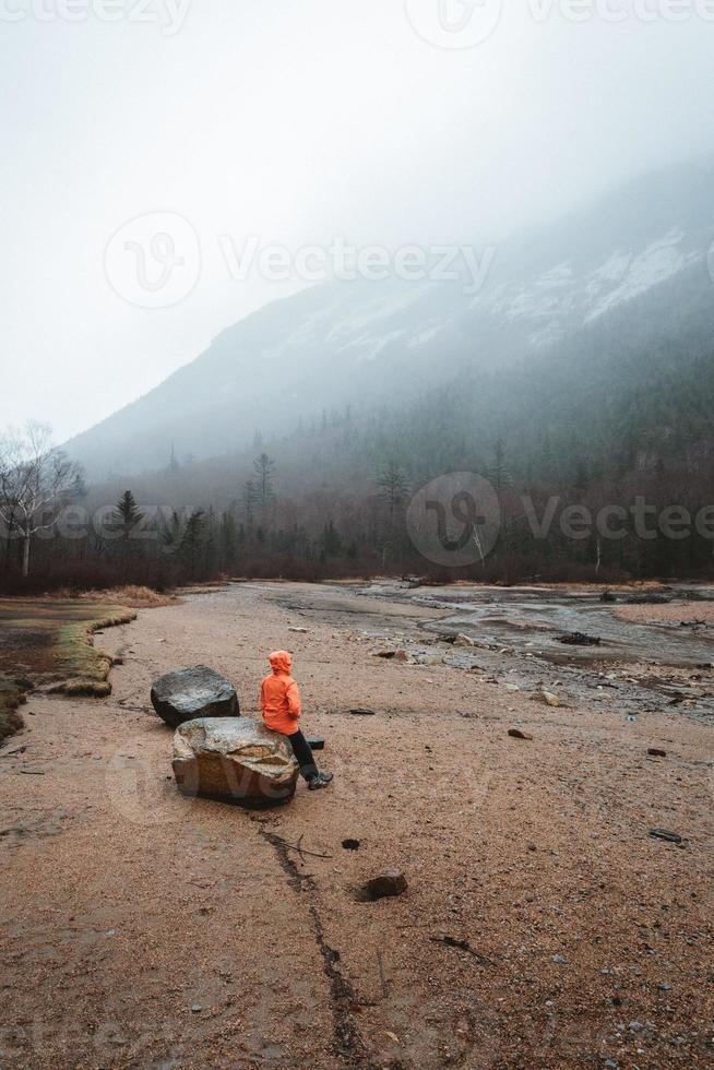 Person, die auf einem Felsen sitzt und die Aussicht genießt foto