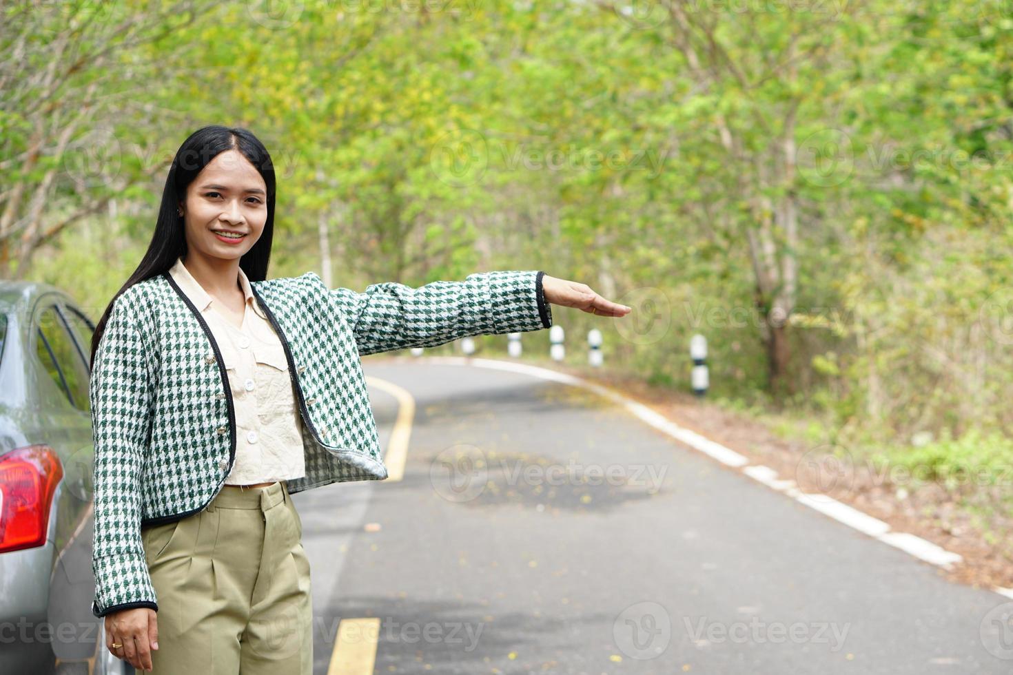 asiatische frau ruft einen mechaniker an, das auto fährt auf die straße um den wald. foto