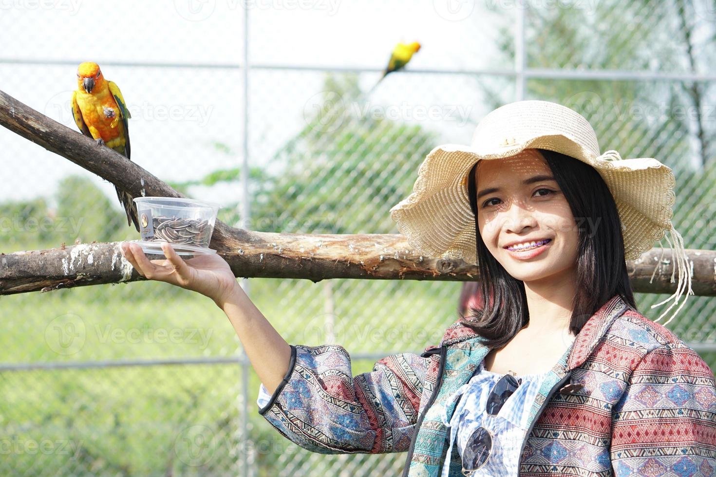 asiatische Frau, die glücklich lächelt, füttert den Papagei foto