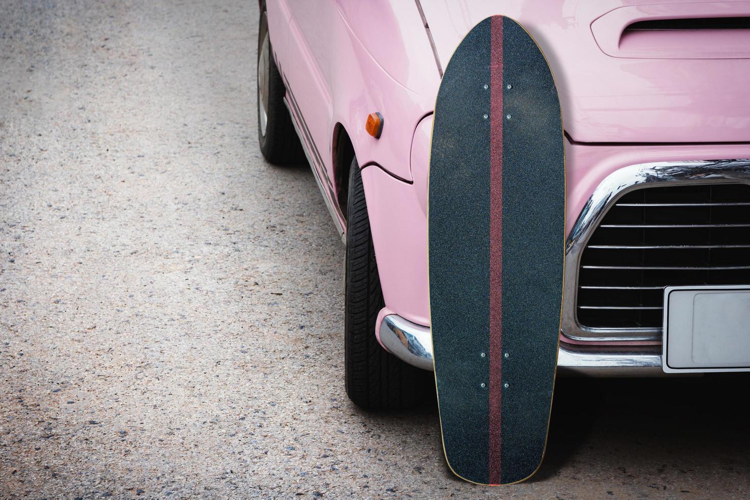 Alter Surfskate mit rosafarbenem Oldtimer auf der Straße auf dem Parkplatz. foto