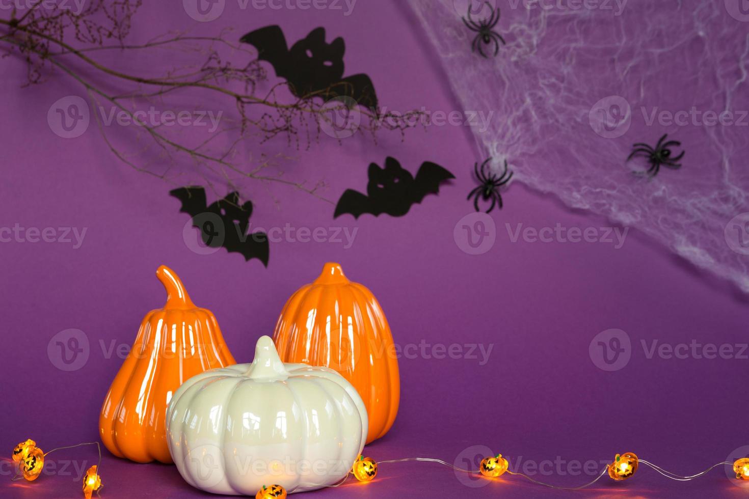 Halloween-Hintergründe aus weißen, orangefarbenen und goldenen Kürbissen, Spinnen und schwarzen Fledermäusen auf einem violetten Hintergrund mit Spinnweben und schrecklicher Landschaft. horror und ein gruseliger urlaub mit kopierraum foto