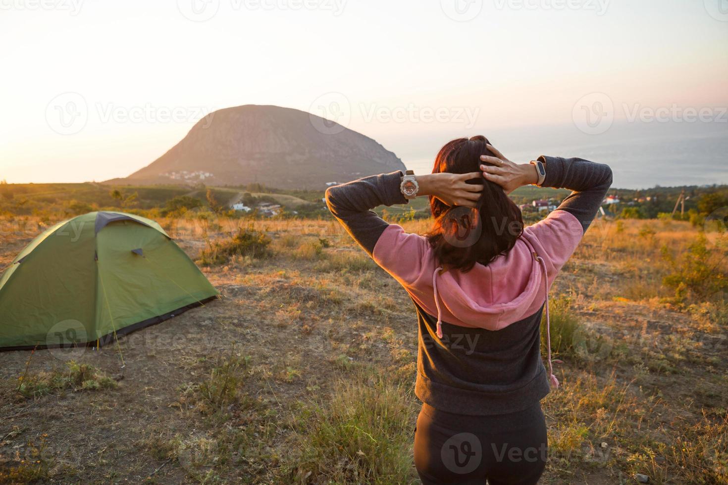 Frau begegnet der Morgendämmerung in den Bergen, freut sich über die Sonne. Panoramablick auf die Berge und das Meer von oben. Camping, Outdoor-Aktivitäten, Sportbergwandern, Familienreisen. ayu-dag, krim. foto