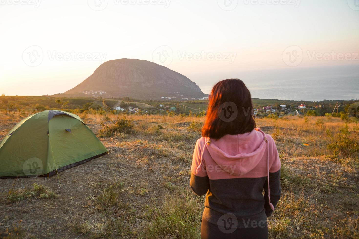 Frau begegnet der Morgendämmerung in den Bergen, freut sich über die Sonne. Panoramablick auf die Berge und das Meer von oben. Camping, Outdoor-Aktivitäten, Sportbergwandern, Familienreisen. ayu-dag, krim. foto