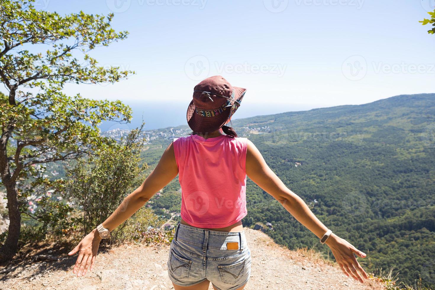 Touristin mit erhobenen Händen blickt auf den Panoramablick auf den Gipfel des Berges und freut sich, genießt Freiheit und Abenteuer. Trekking, Reisen, aktiver Ökotourismus, gesunder Lebensstil, Wandern foto