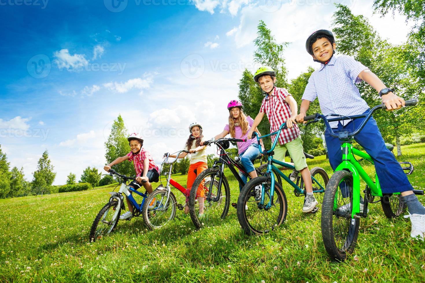 Reihe von Kindern in bunten Helmen, die Fahrräder halten foto