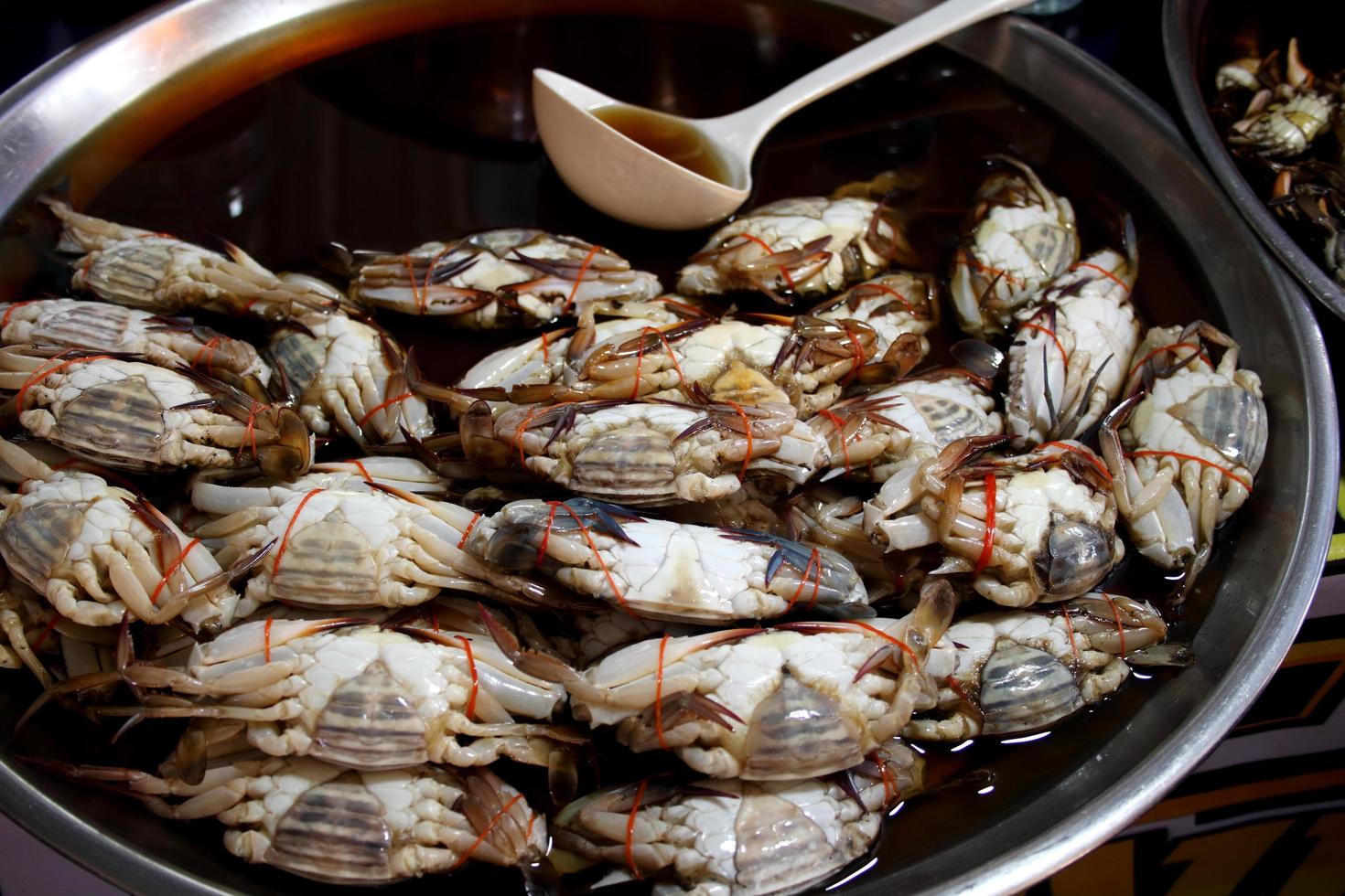 Blaue schwimmende Krabben, die durch Fischsauce konserviert werden, sind auf einem Tablett für den Verkauf in Thailand. foto