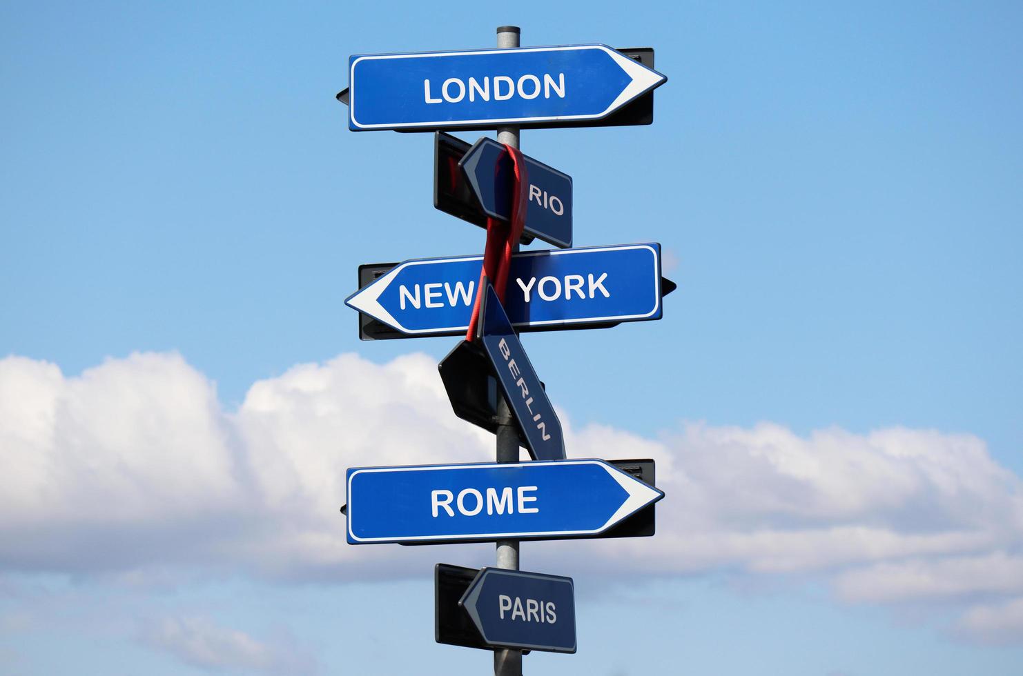 Straßenschild mit den Namen der Hauptstädte auf blauem Himmelshintergrund isoliert. London, New York, Rom, Paris, Rio, Berlin. foto