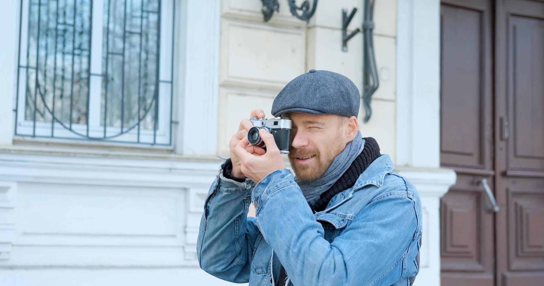 junger gutaussehender männlicher reisender mit filmkamera macht straßenfotos foto