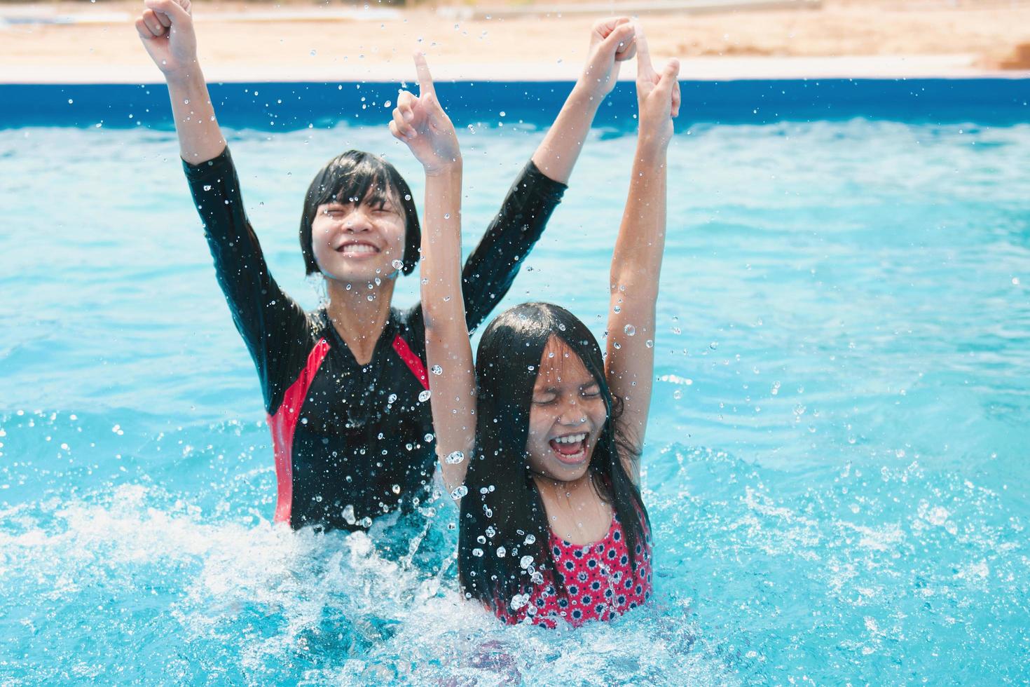 Kinder schwimmen und spielen im Pool mit fröhlichem Lächeln foto