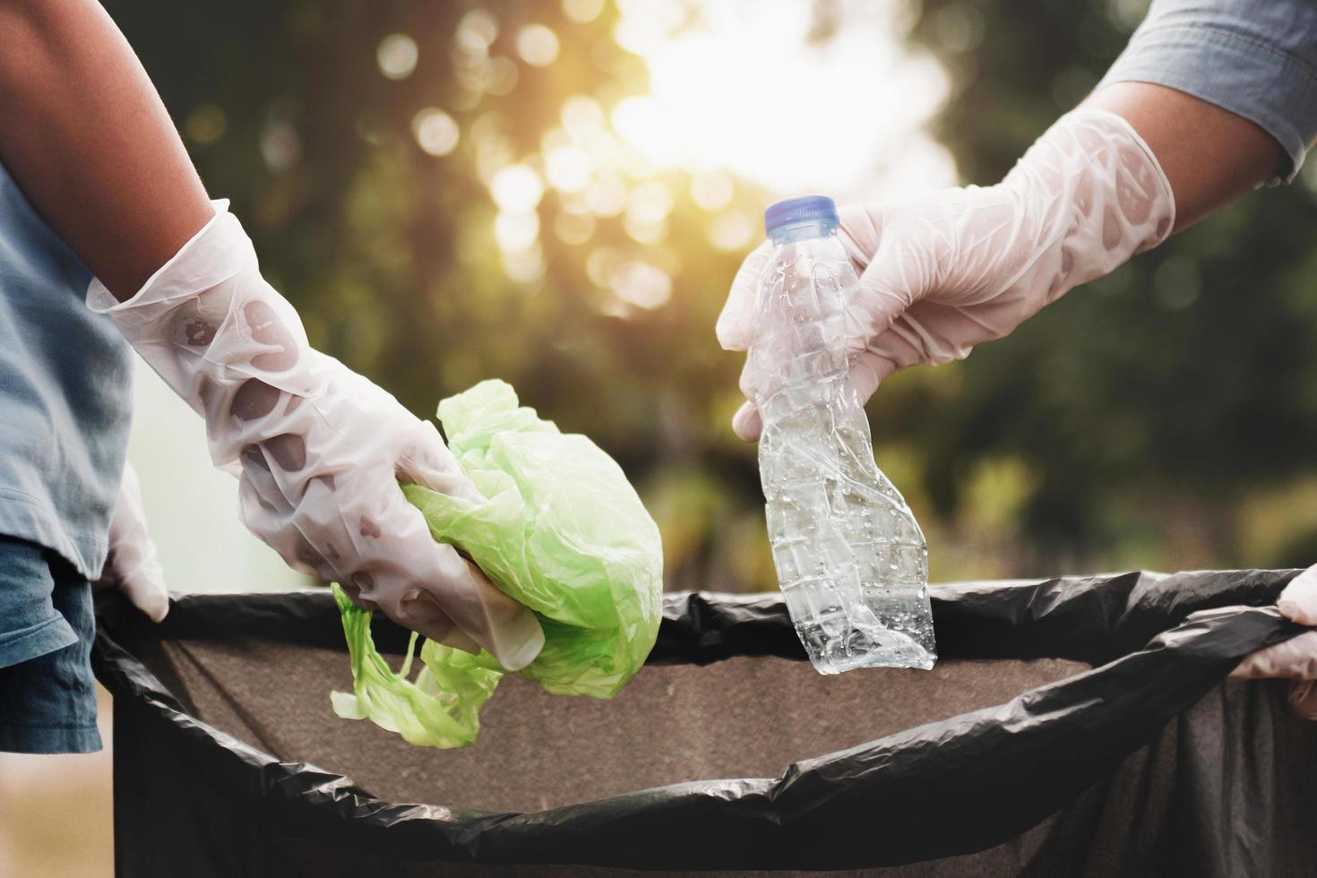 frauenhand, die müllplastik zur reinigung im park aufsammelt foto